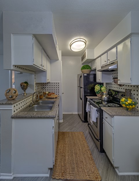 A kitchen with white cabinets and a black refrigerator.